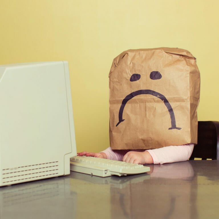 Employee with paper bag with sad face drawn on over their head