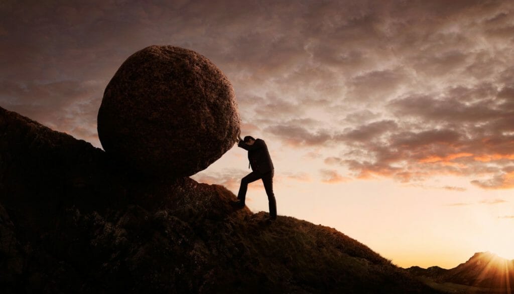 Man pushing boulder up mountain
