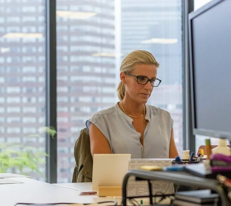 Manager sits behind desk at office