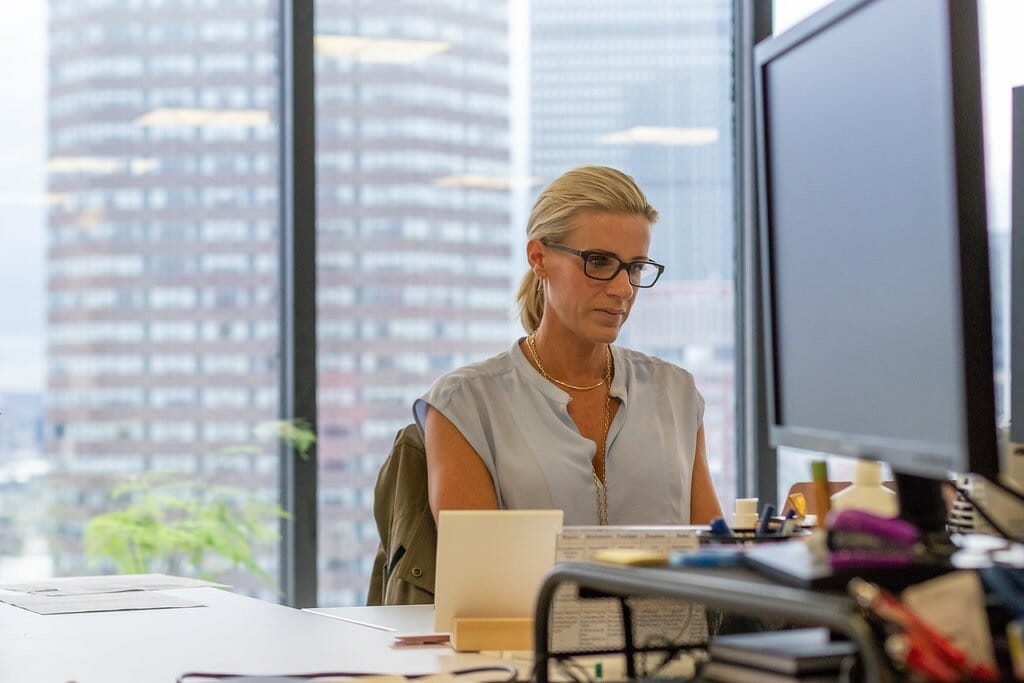 Manager sits behind desk at office