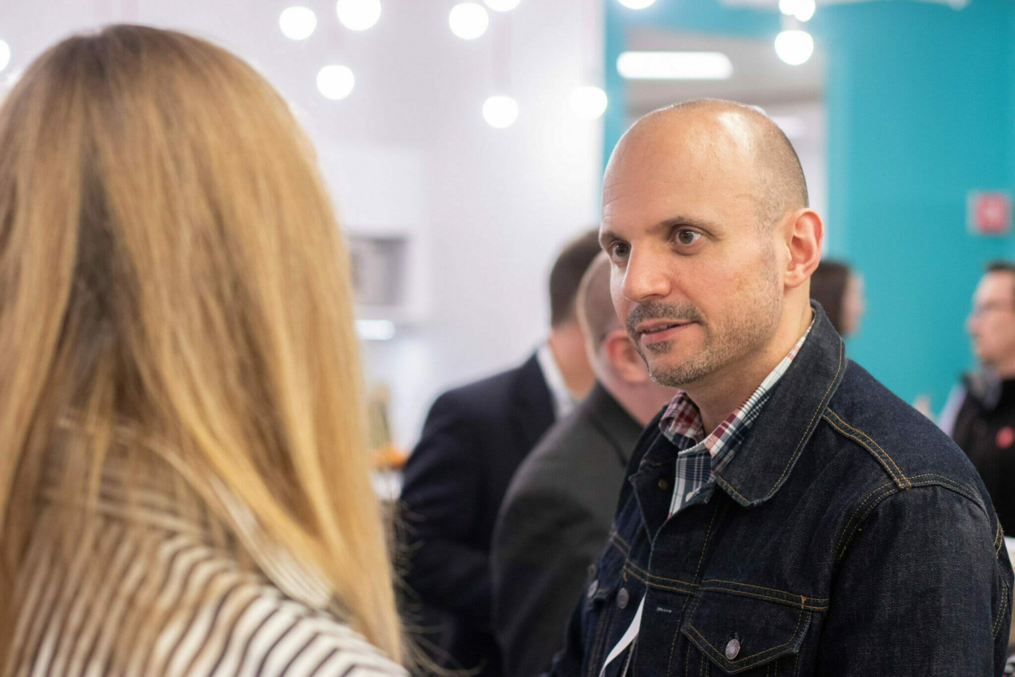 Two diverse employees talk at office event